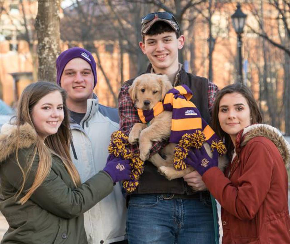 Students & puppy dressed in Alfred University gear